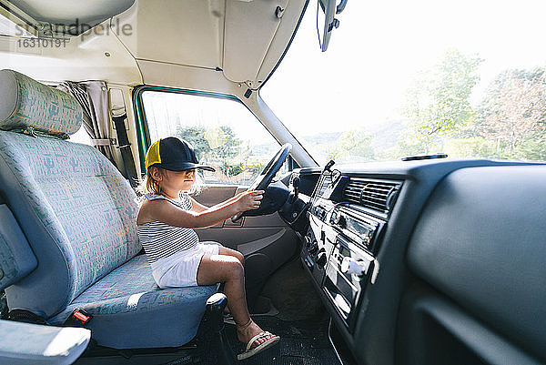 Mädchen mit Mütze auf dem Fahrersitz eines Wohnmobils