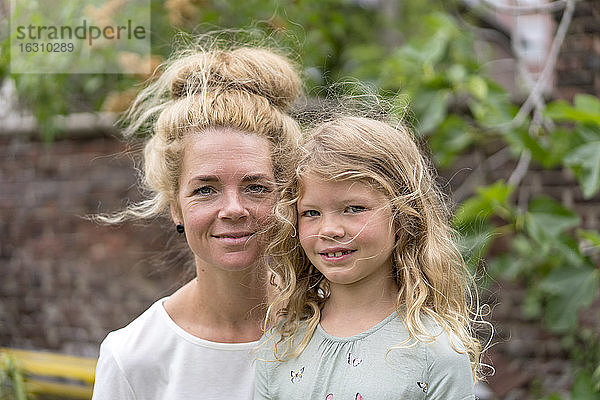 Lächelnde blonde Frau mit Tochter im Hinterhof