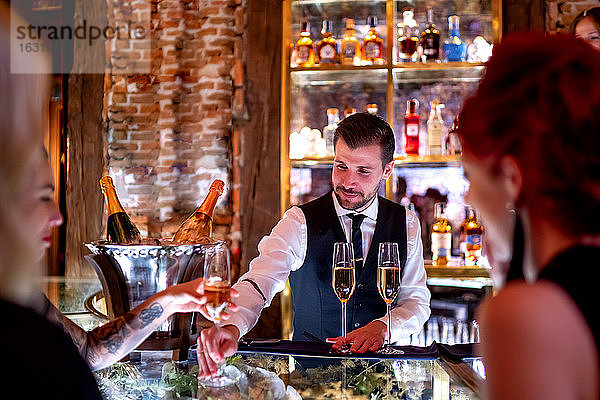 Barkeeper serviert Frauen an der Theke eines Pubs Getränke