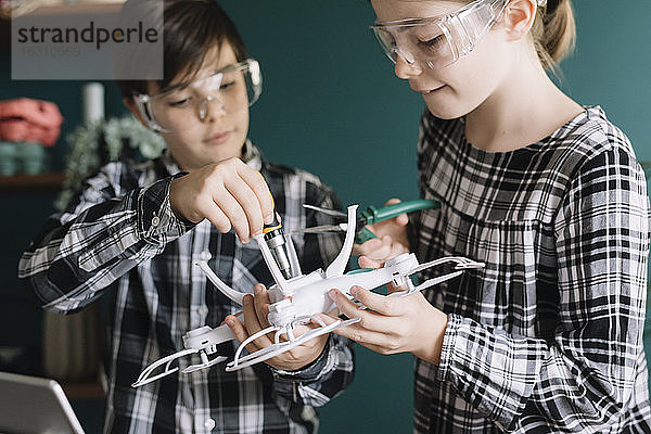 Nahaufnahme von Geschwistern  die zu Hause eine Drohne bauen