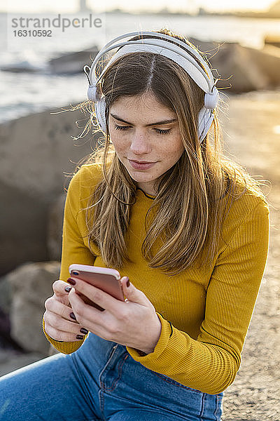 Nachdenkliche Frau mit Handy beim Musikhören in der Stadt
