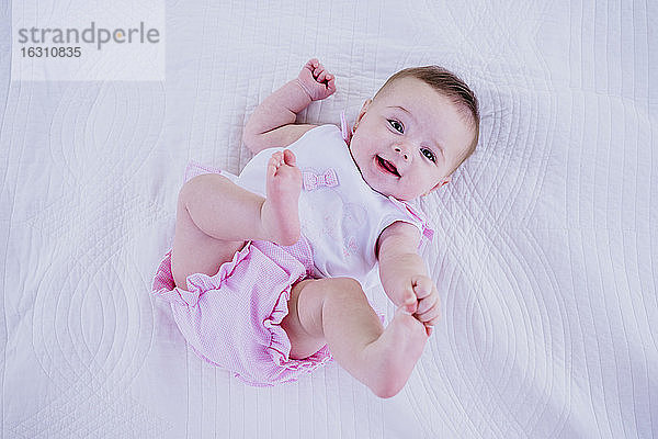 Baby-Mädchen berührt die Zehen  während es auf einer Decke liegt