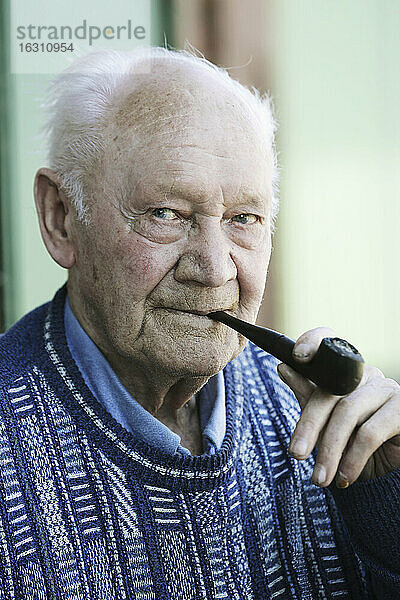Deutschland  Porträt eines älteren Mannes mit Pfeife  Nahaufnahme