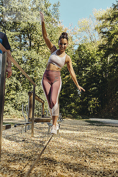 Frau balanciert auf einem Seil auf einem Fitnessparcours