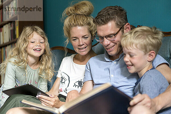 Glückliche Familie beim Betrachten eines Fotoalbums  während sie zu Hause sitzt