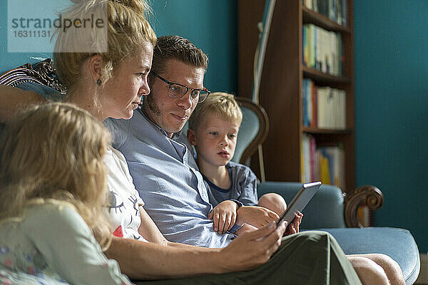 Familie mit digitalem Tablet auf dem Sofa im heimischen Wohnzimmer