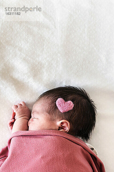 Neugeborenes Baby Mädchen mit Herzform auf dem Kopf schlafen über Bett im Krankenhaus