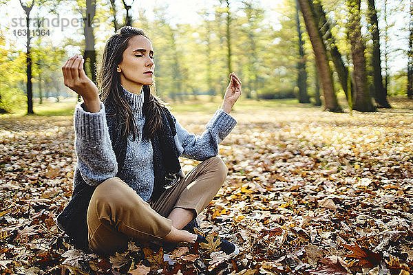 Junge Frau meditiert im Herbstwald