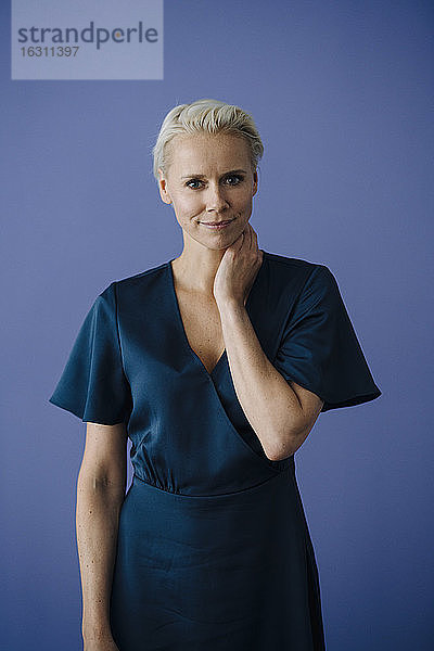Selbstbewusste Geschäftsfrau mit kurzen Haaren vor blauem Hintergrund
