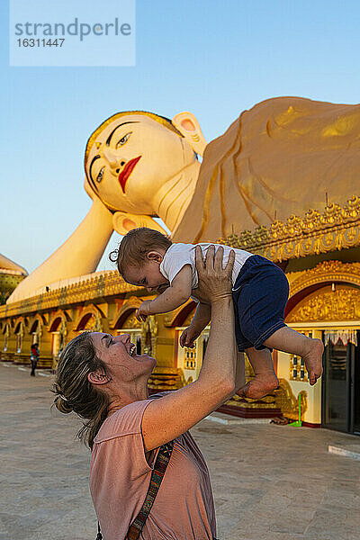 Myanmar  Mon-Staat  Mutter hält kleines Mädchen vor der riesigen Statue eines liegenden Buddhas im Pupawadoy-Kloster