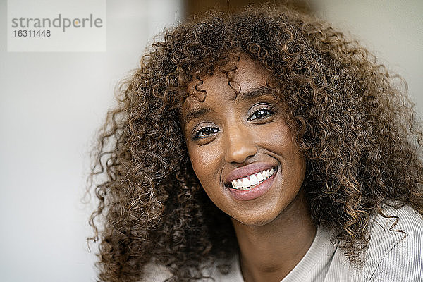 Nahaufnahme einer lächelnden Unternehmerin mit lockigem Haar im Büro