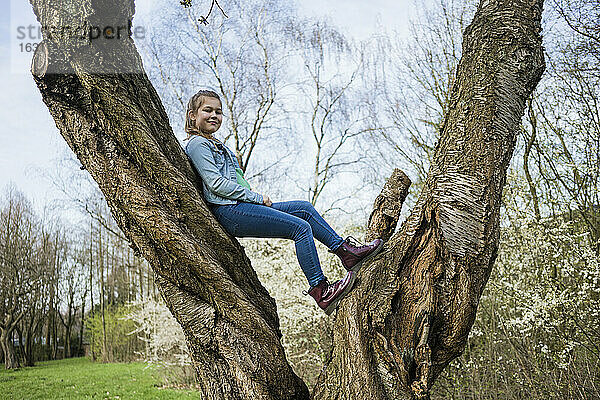 Lächelndes Mädchen balanciert über einen Baumstamm im Park