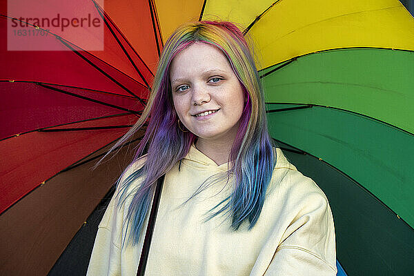 Porträt einer jungen Frau mit gefärbtem Haar unter einem Regenschirm