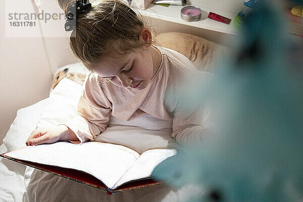 Mädchen  das im Schlafzimmer sitzend ein Buch liest