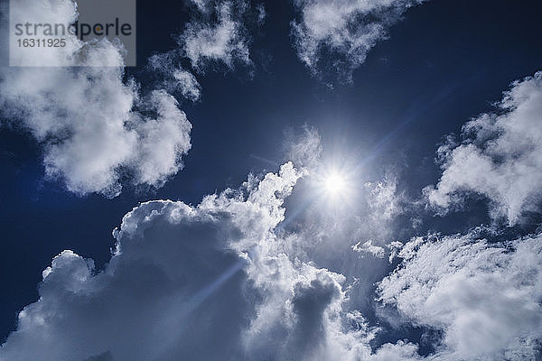 Weiße Wolken und Sonne am blauen Himmel