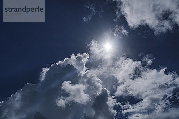 Weiße Wolken und Sonne am blauen Himmel