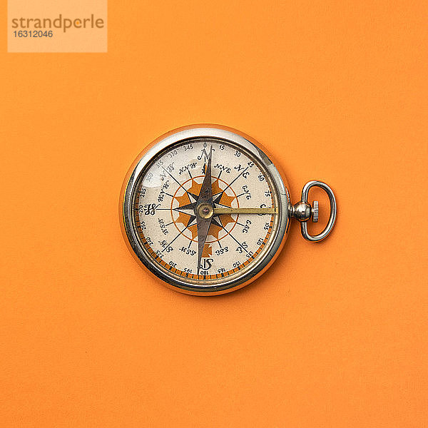Antiker Kompass auf orangem Hintergrund