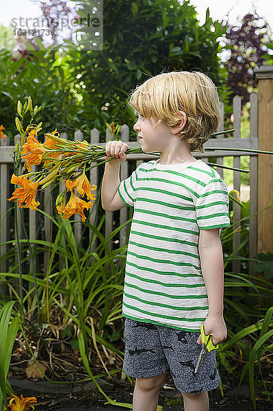 Junge (4-5) mit Blumen im Garten