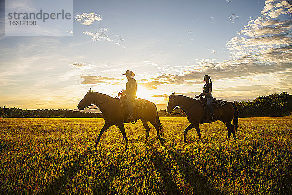 USA  Utah  Salem  Vater und Tochter (14-15) reiten Pferde bei Sonnenuntergang