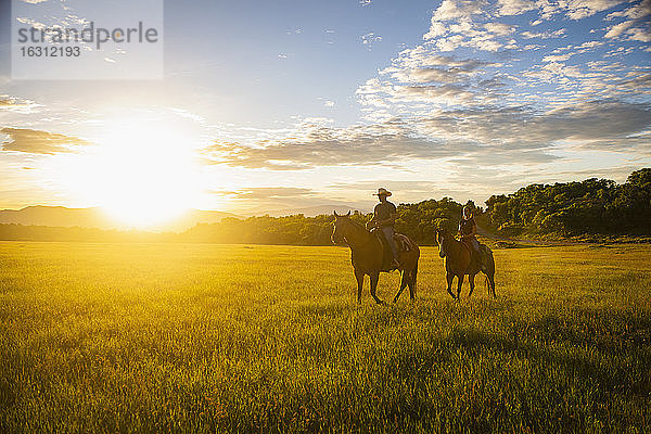 USA  Utah  Salem  Vater und Tochter (14-15) reiten Pferde bei Sonnenuntergang
