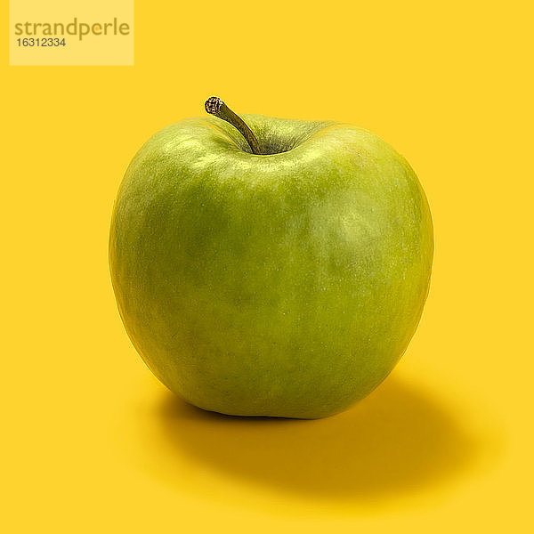 Grüner Apfel vor gelbem Hintergrund