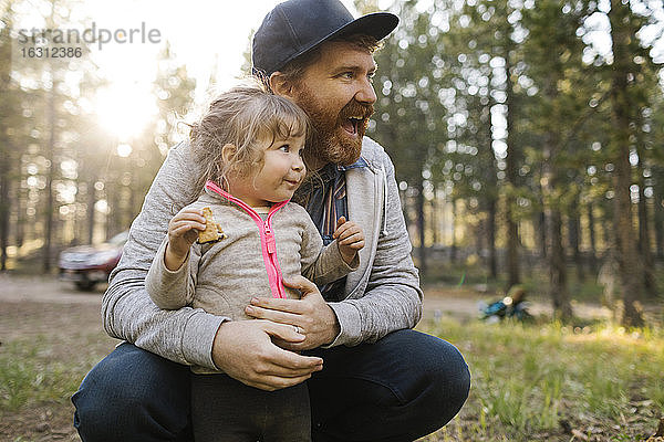 Lächelnder Mann mit Tochter (2-3) auf Schoß im Wald  Wasatch Cache National Forest