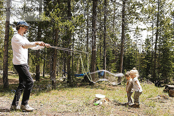 Vater macht große Seifenblasen im Wald für zwei Töchter (2-3  4-5)  Wasatch-Cache National Forest