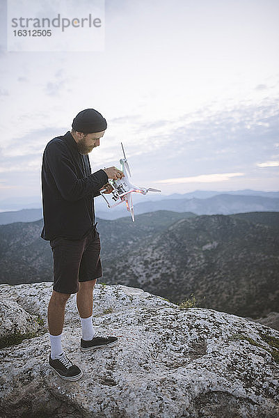 Italien  Ligurien  La Spezia  Mann auf Berggipfel mit Drohne