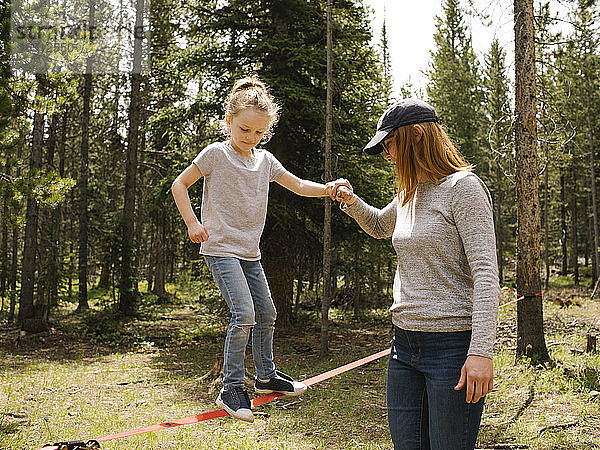 Mutter assistiert Tochter (6-7) beim Slackline-Gehen im Wald  Wasatch-Cache National Forest