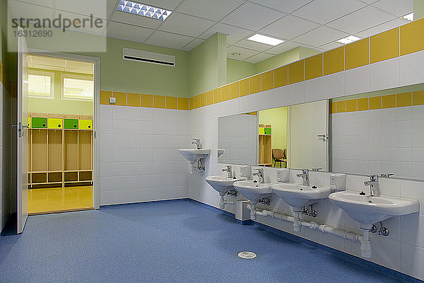 Schultoilette  moderner Stil mit gelber Farbe und blauem Bodenbelag