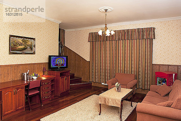Ein Hotel mit altmodischen Zimmern im Retro-Stil und rustikalen Gegenständen  Sofa und Stühlen und Fernseher.
