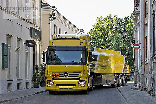 Großer gelber Lastwagen in einer engen Straße  der um eine Ecke biegt  ein Tankwagen.