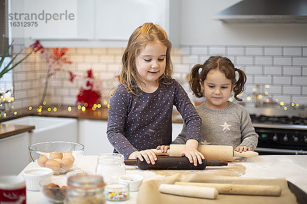 Zwei Mädchen stehen in der Küche und backen Weihnachtsplätzchen.