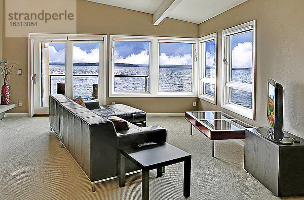 Ein Wohnzimmer in einem Haus am Wasser  mit einem großen Fenster und Meerblick.