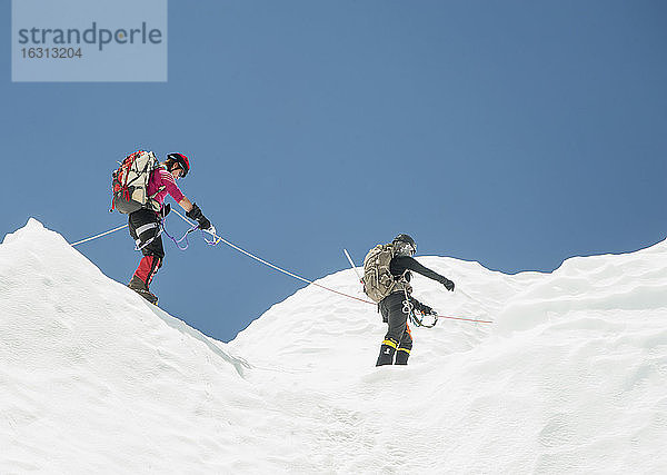 Zwei Bergsteiger im Schnee auf einem Berg  zusammen angeseilt.