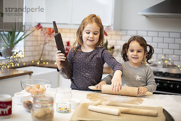 Zwei Mädchen stehen in der Küche und backen Weihnachtsplätzchen.