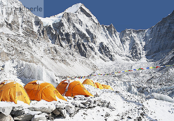 Eine Gruppe orangefarbener Zelte in einem Basislager für Bergsteiger in der Himalaya-Region.