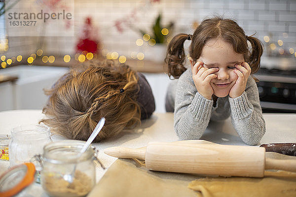 Zwei Mädchen stehen in der Küche und backen Weihnachtsplätzchen.