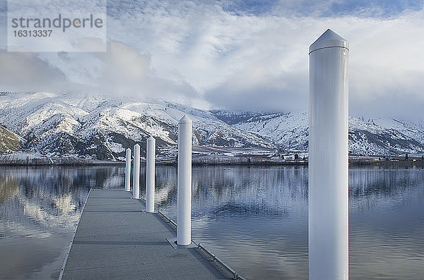 Pfeiler auf dem Dock am See in der Nähe der schneebedeckten Bergkette
