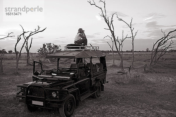Frau  die auf einem 4x4 steht  der im Moremi-Reservat in Botswana geparkt ist.