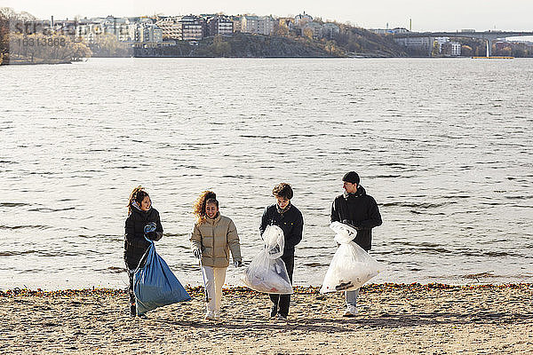 Junge männliche und weibliche Umweltschützer mit gesammelten Mikroplastiken gehen gegen den See