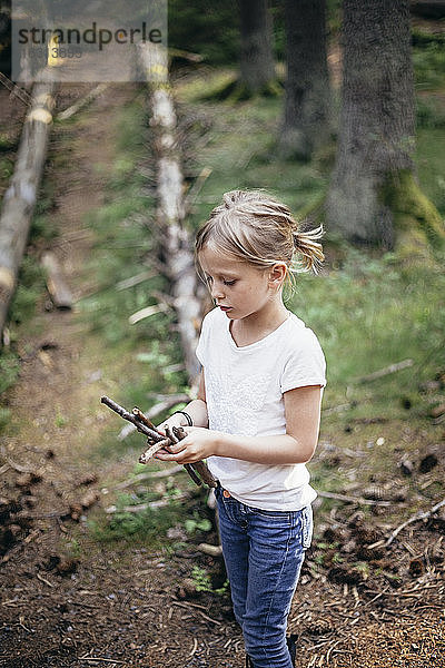 Mädchen hält Stöcke im Wald
