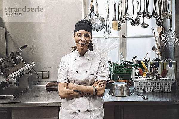 Porträt einer lächelnden Köchin mit verschränkten Armen in einer Großküche
