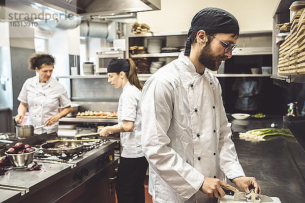 Männlicher Chefkoch schneidet Pilze in Großküche