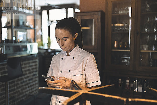 Köchin benutzt Smartphone im Restaurant