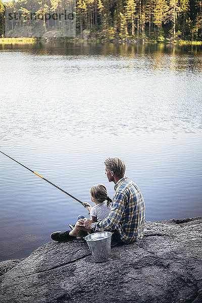 Vater und Tochter beim Angeln am See sitzend