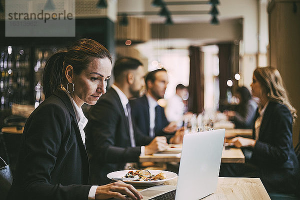 Seitenansicht einer Geschäftsfrau mit Laptop im Restaurant