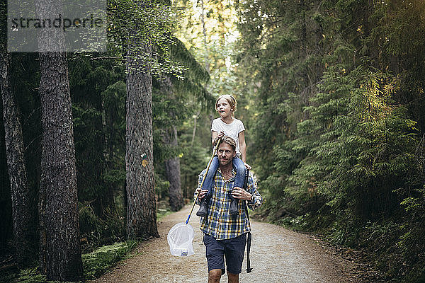Vater trägt Tochter auf der Schulter beim Waldspaziergang