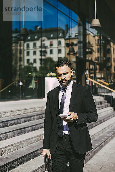 Geschäftsmann benutzt Smartphone beim Spaziergang in der Stadt