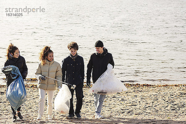 Männliche und weibliche Umweltschützer mit Mikroplastikmüll  die gegen den See laufen